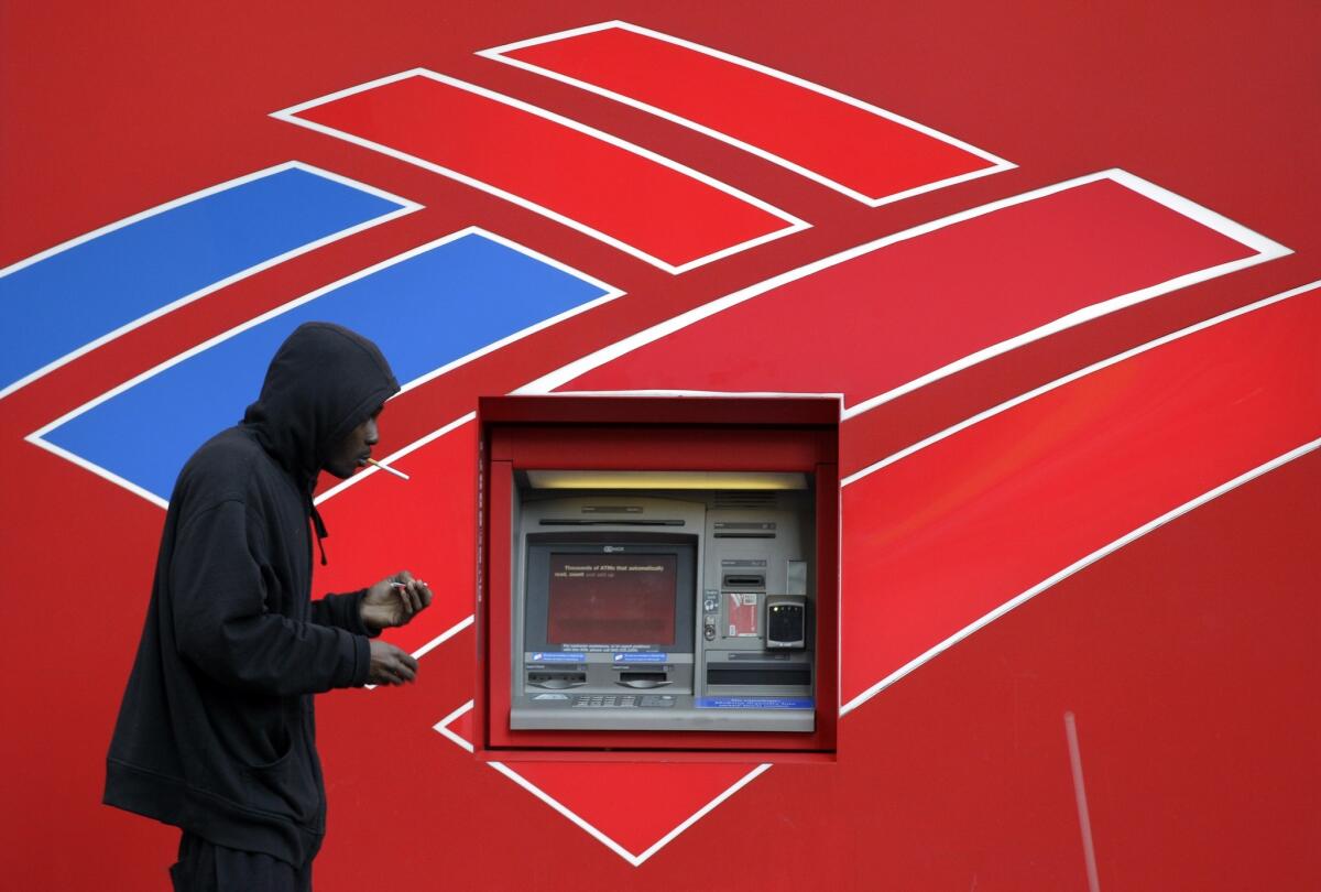 A man walks past an ATM outside the Bank of America headquarters in Charlotte, N.C.