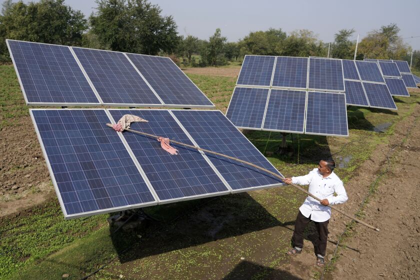 FILE - Farmer Pravinbhai Parmar cleans a solar panel installed at a farm in Dhundi village of Kheda district in western Indian Gujarat state, India, Friday, Jan. 13, 2023. The Indian government will not consider any proposals for new coal plants for the next five years and focus on growing its renewables sector, according to an updated national electricity plan released Wednesday evening. (AP Photo/Ajit Solanki, File)