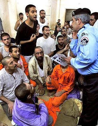 An Iraqi prisoner speaks to Interior Ministry spokesman Maj. Gen. Abdul-Kareem Khalaf while he escorts the news media on a tour of the National Police detention center in northwest Baghdad.