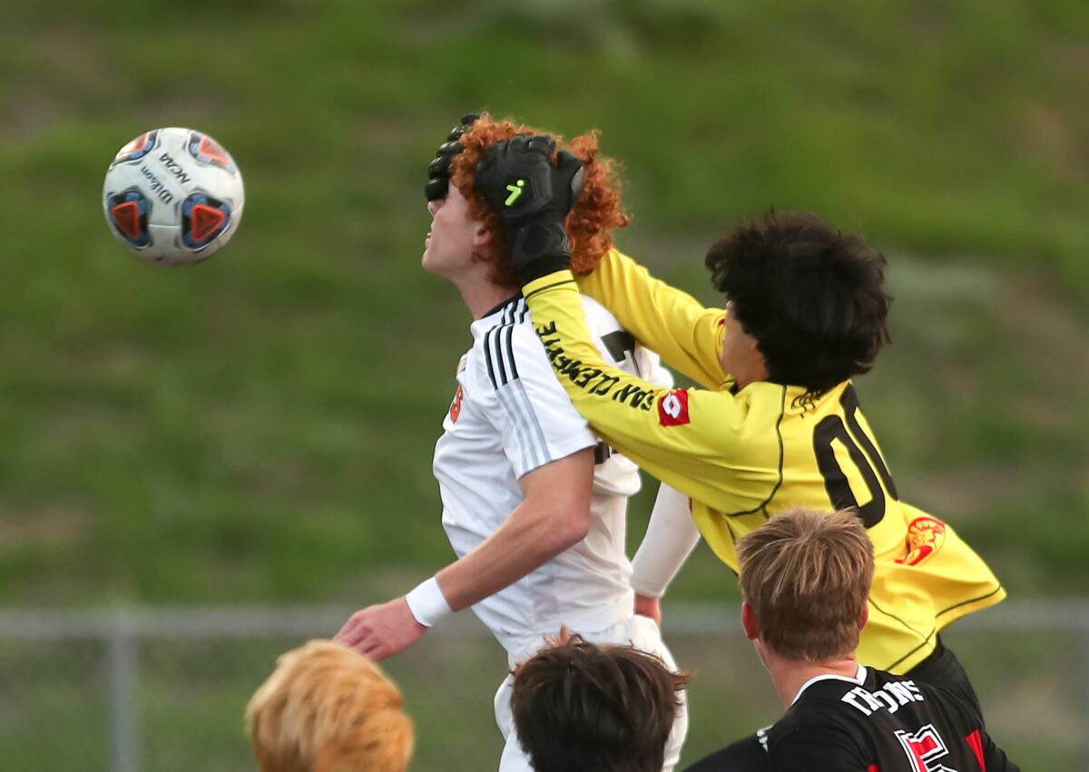 San Clemente's Ryan Savoie (00) goes up to grab the ball but instead catches the head of Huntington Beach's Reid Fisher.