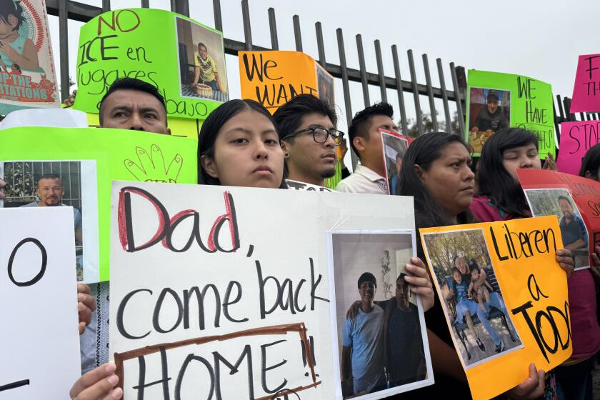 Yurién sostiene un rótulo con la leyenda en inglés: "Papá, vuelve a casa", en una conferencia