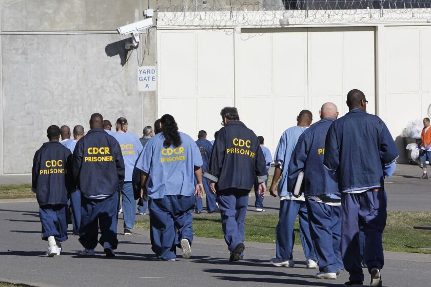FILE - Inmates walk through the exercise yard at California State Prison Sacramento, near Folsom, Calif., on Feb. 26, 2013. Former California correctional officer Arturo Pacheco, who was fired from his job in 2018, pleaded guilty Monday, July 25, 2022, to federal charges stemming from two on-duty assaults in 2016. A second correctional officer who also was fired in 2018 previously pleaded guilty to submitting a false report about Pacheco's actions. Both officers worked at California State Prison, Sacramento, which neighbors Folsom State Prison east of Sacramento. (AP Photo/Rich Pedroncelli, File)
