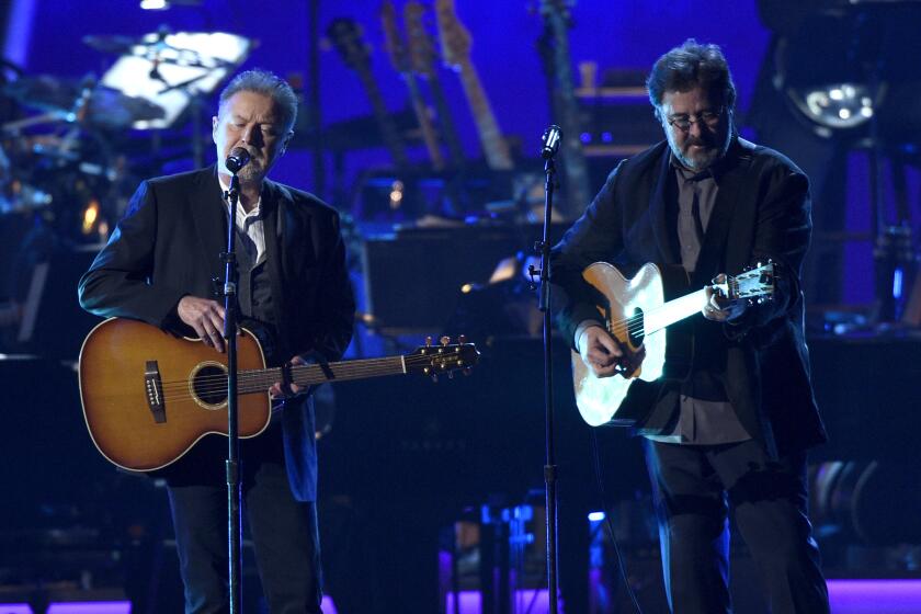 Don Henley, left, and Vince Gill of the Eagles play guitars onstage