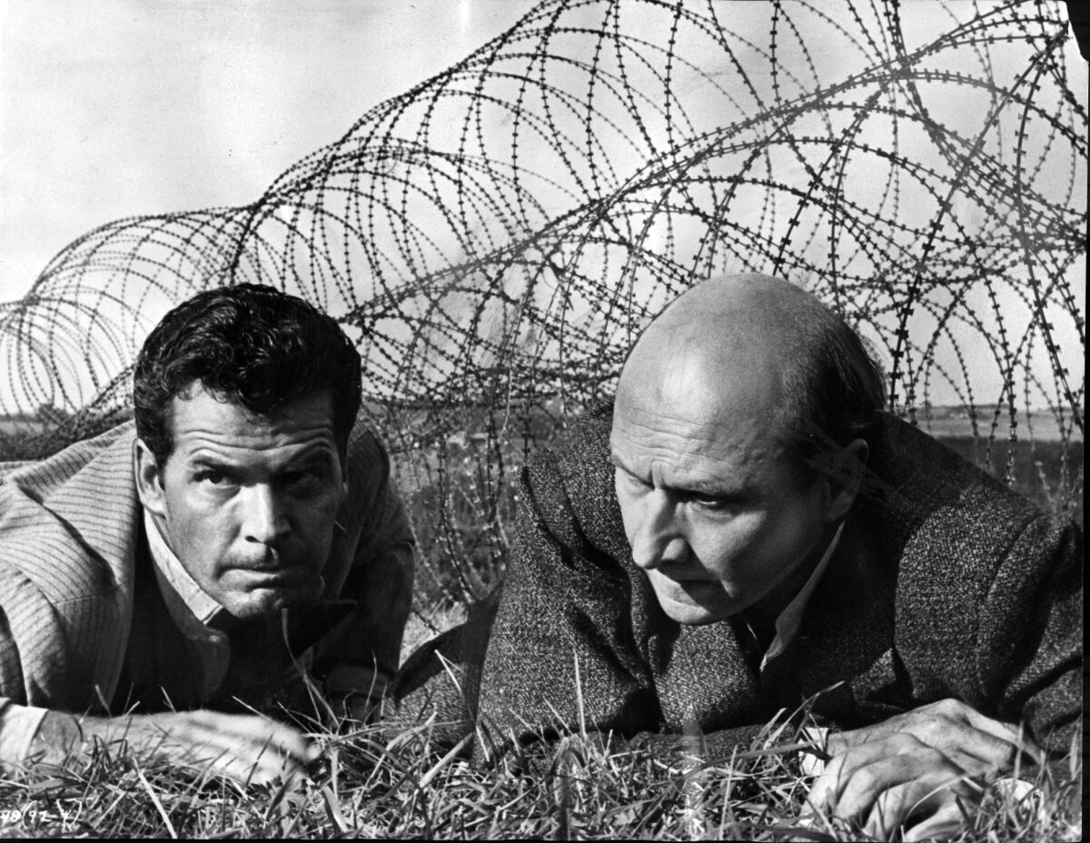 James Garner, left, and Donald Pleasance crawl under a barbwire fenc in the 1963 movie "The Great Escape."