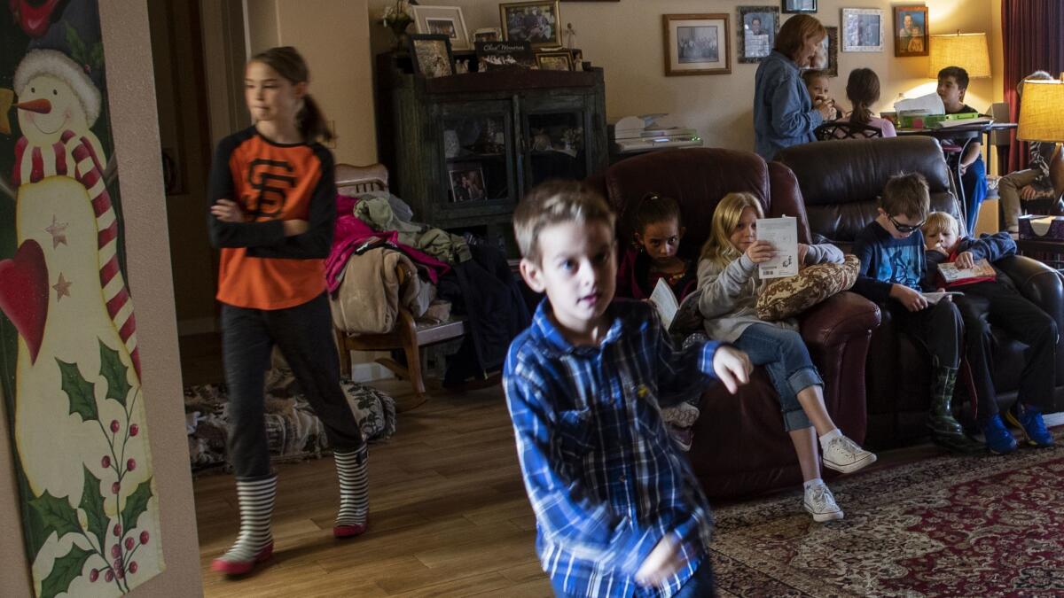 Rowan Reynolds, 8, runs to retrieve something from his backpack as children read "Charlotte's Web" in the living room during literature class at teacher Sheri Eichar's home. In the background, Eichar teaches science at the dining room table.