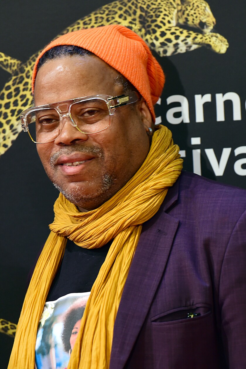 A man in a yellow scarf, purple sports coat and orange skip cap.