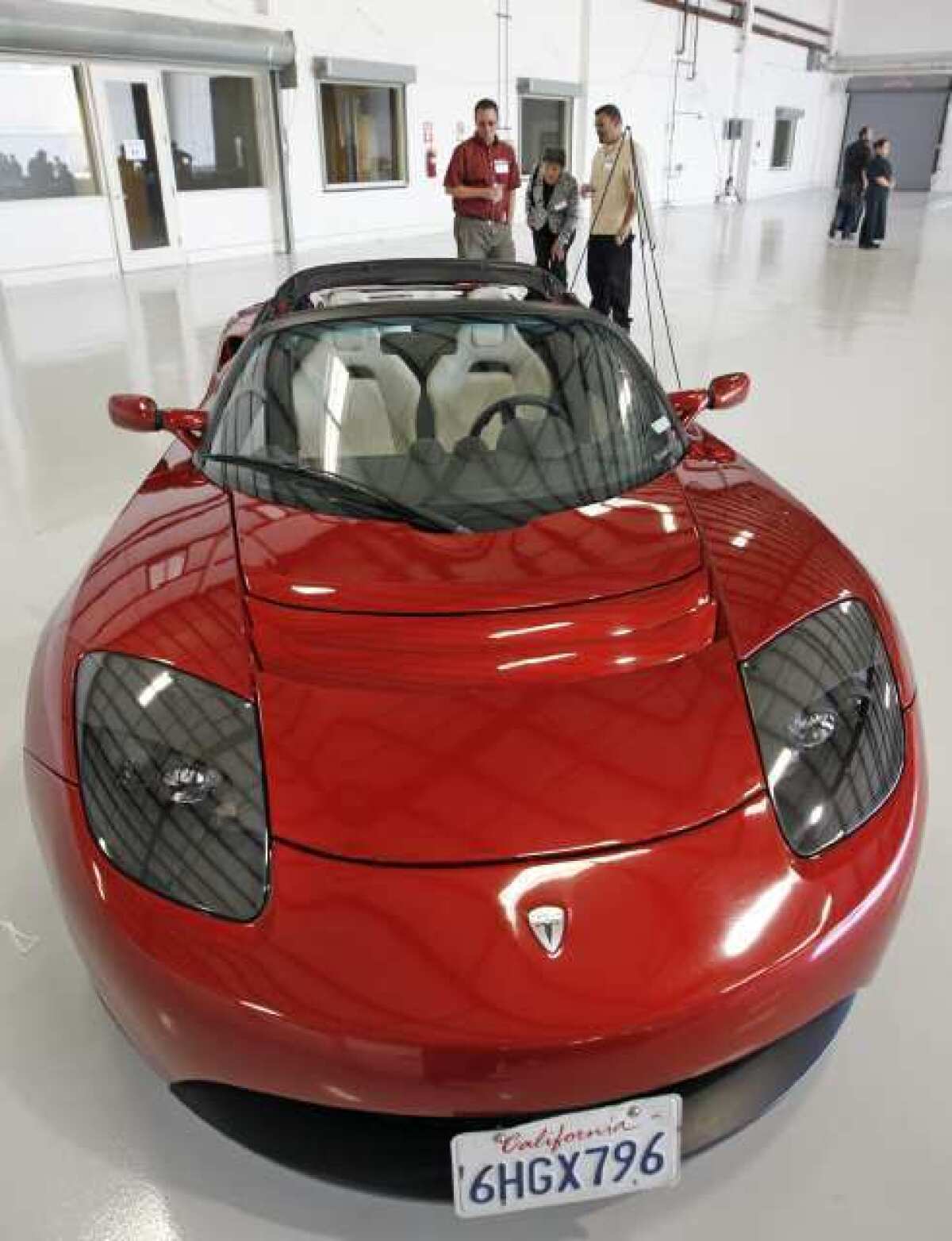 Attendees of a Electric Vehicle Event and Ride & Drive at the Bob Hope Airport take a closer look at a Tesla Roadster.