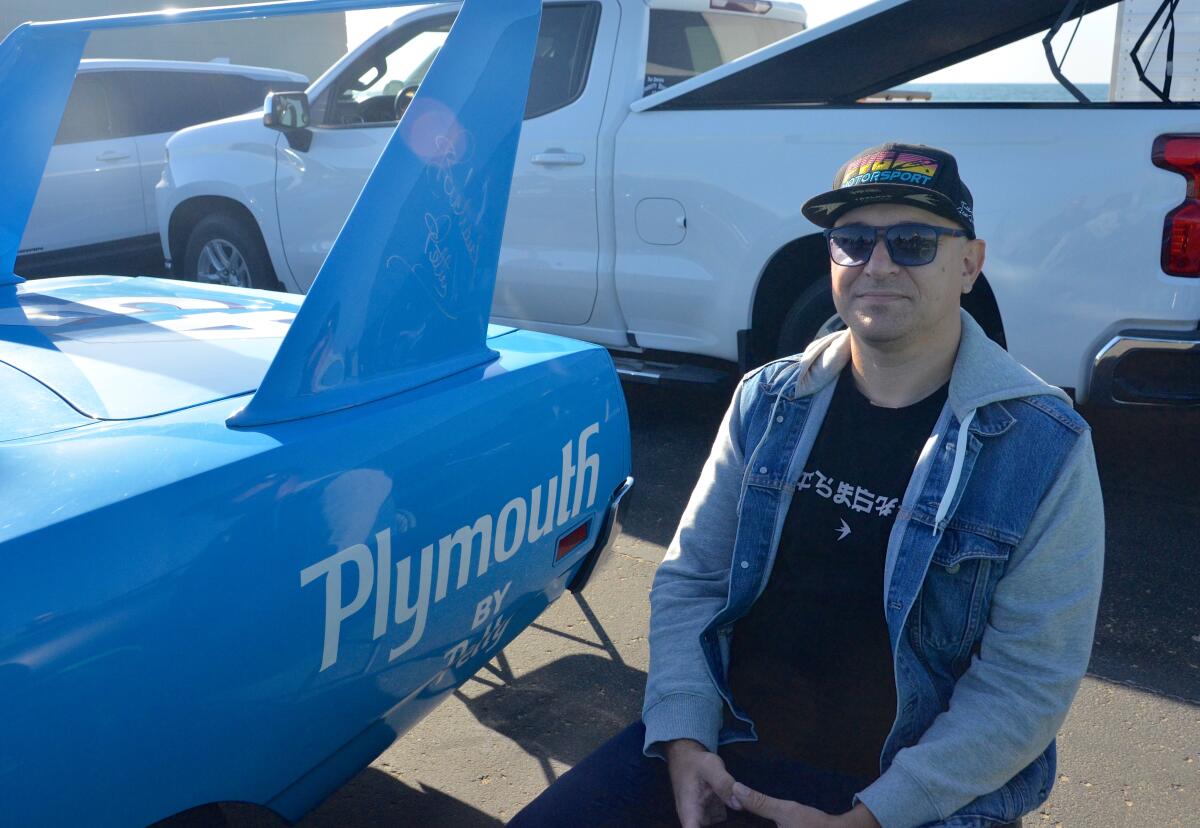 Timothy Kosharnyi sits next to the Tom Petty autographed 1970 Plymouth Superbird.