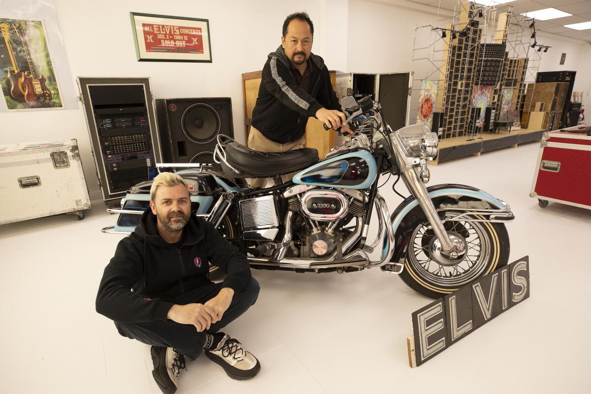 Two men posing with a Harley motorcycle