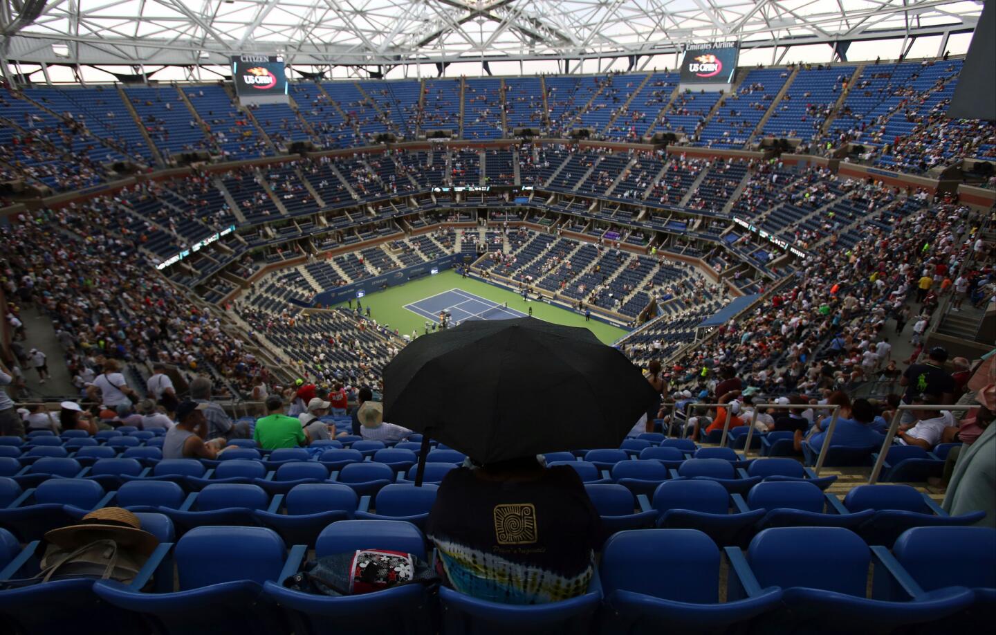 A spectator holds an umbrella during a rain delay in the quarterfinal match between Victoria Azarenka, of Belarus, and Simona Halep, of Romania, at the U.S. Open tennis tournament, Wednesday, Sept. 9, 2015, in New York. (AP Photo/Adam Hunger)