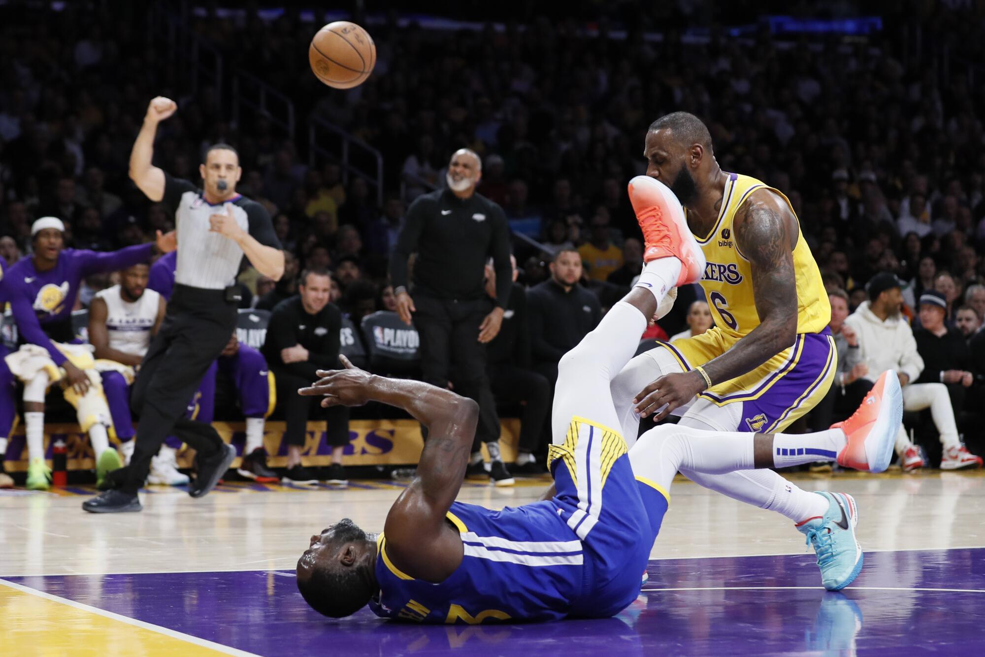 Warriors forward Draymond Green hits his head on the court after being fouled by Lakers star LeBron James.