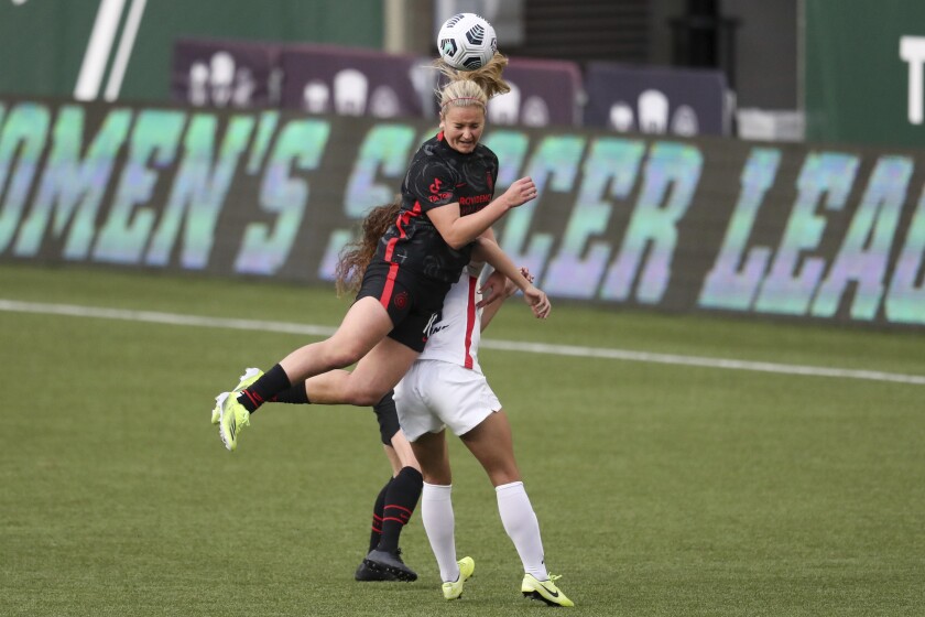 FILE - Portland Thorn's Lindsey Horan (10) jumps over OL Reign's Angelina (26) for a header during an NWSL Challenge Cup soccer match, Wednesday, April 21, 2021, in Portland, Ore. Thorns midfielder Lindsey Horan has been loaned to French club Lyon through the summer of 2023. Horan has been with the Thorns since 2016. In addition to the loan to Lyon, Portland announced Thursday, Jan. 27, 2022, that she had signed a contract extension with the Thorns through the 2025 season.(AP Photo/Amanda Loman, File)
