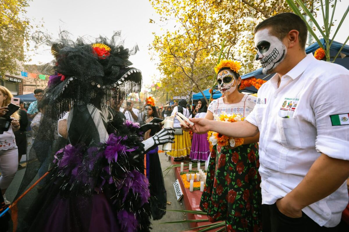 Catrina shares a flame with onlookers at the 2018 Noche de Altares, or Night of Altars event.