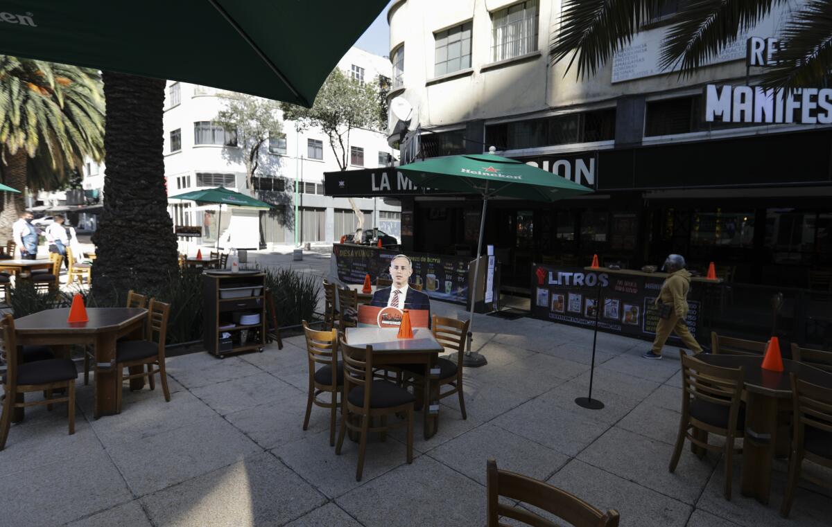 A life-size cutout of Mexican official Hugo Lopez-Gatell at an empty restaurant table outdoors