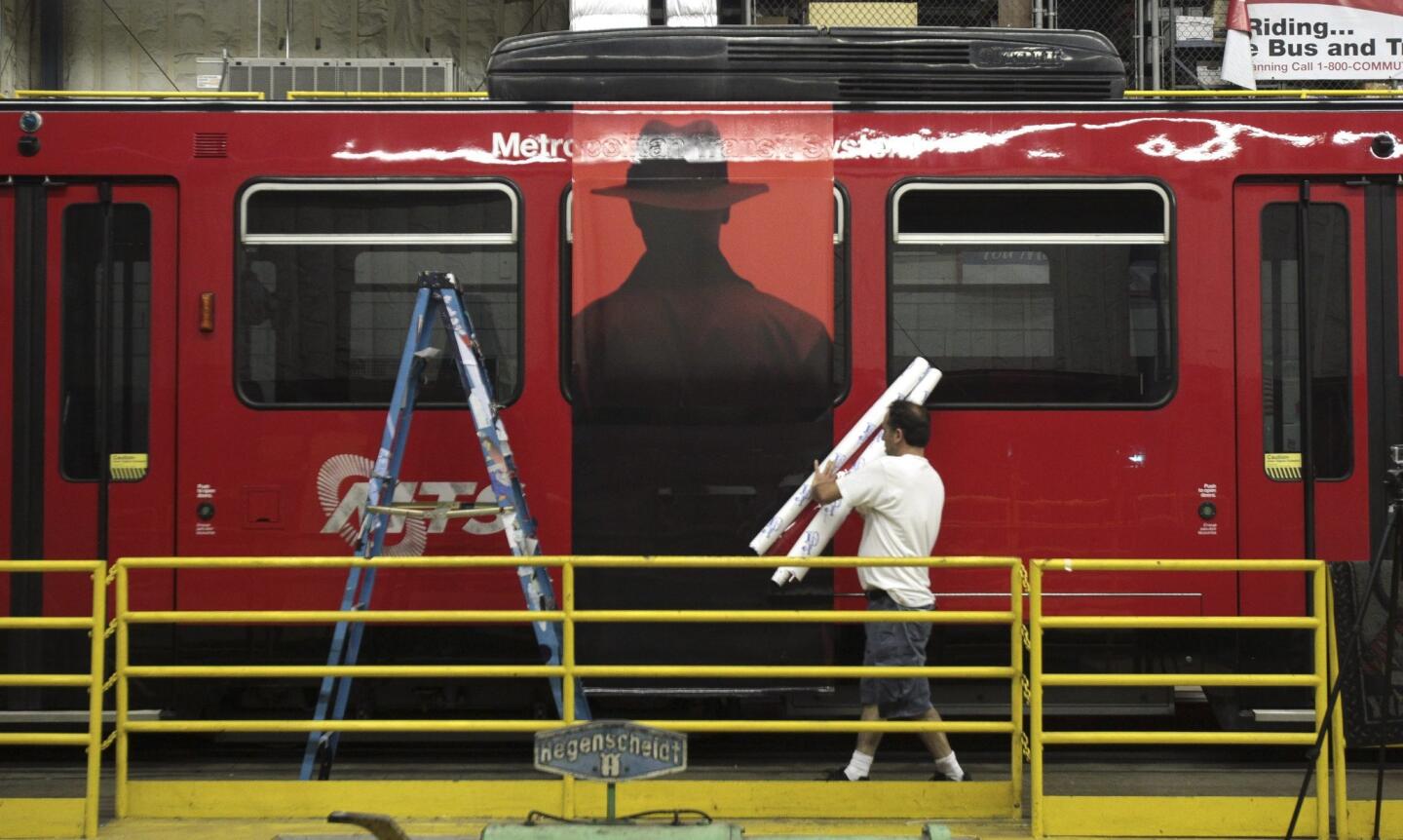 Farzad Parvizi, of Pixel imaging Media, carries rolls of self adhesive transit vinyl as he wraps a trolley car with an advertising wrap for "The Exorcist" television show, part of the fall lineup for the FOX network.
