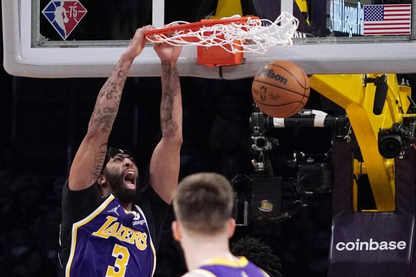 Los Angeles Lakers forward Anthony Davis, left, dunks as guard Austin Reaves watches during the first half of an NBA basketball game against the Utah Jazz Wednesday, Feb. 16, 2022, in Los Angeles. (AP Photo/Mark J. Terrill)