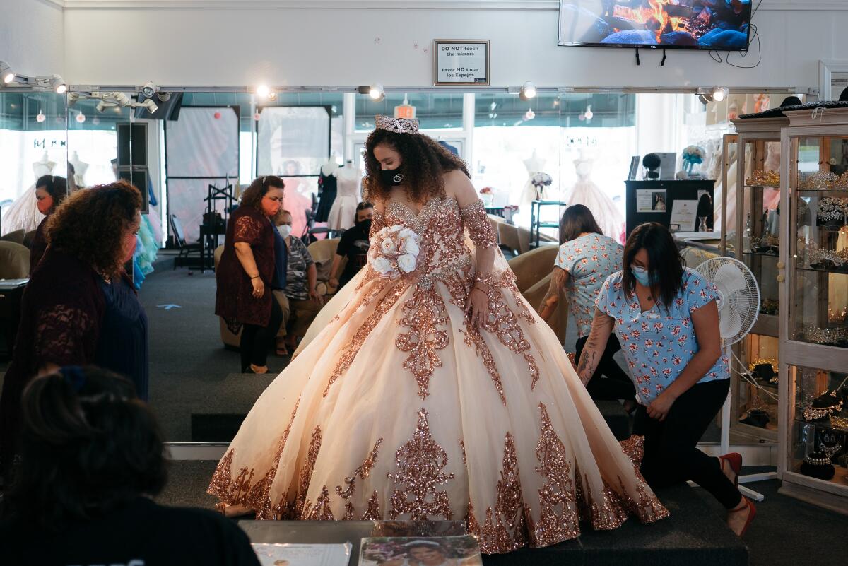 A customer in a mask is fitted for a quinceañera