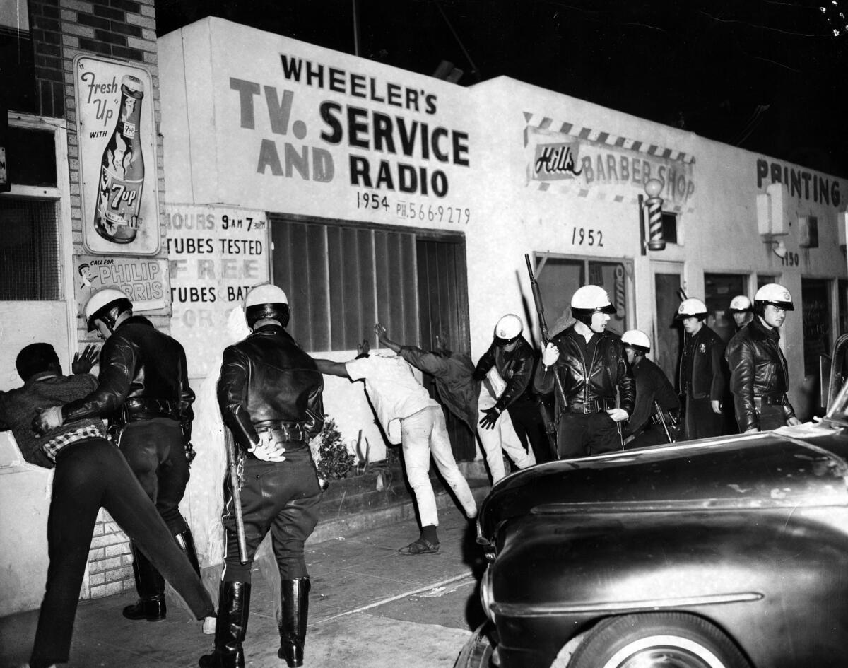 Police officers search for weapons during the Watts Riots in 1965.