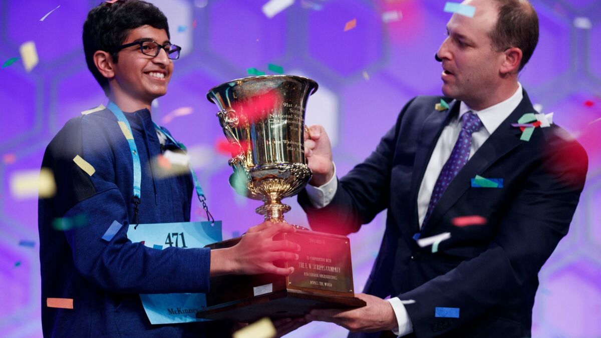 Scripps National Spelling Bee winner Karthik Nemmani receives the championship trophy from Adam Symson, president and CEO of the E.W. Scripps Co.