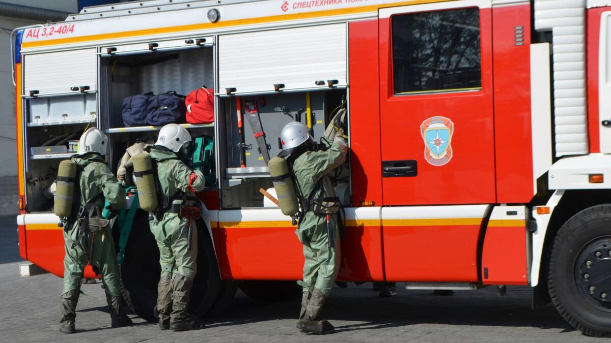 In this Oct. 5, 2016, photo provided by Russia Emergency Situations Ministry press service, the ministry servicemen wearing anti-chemical hazard suits unload firefighters' equipment at an undisclosed location in Russia.
