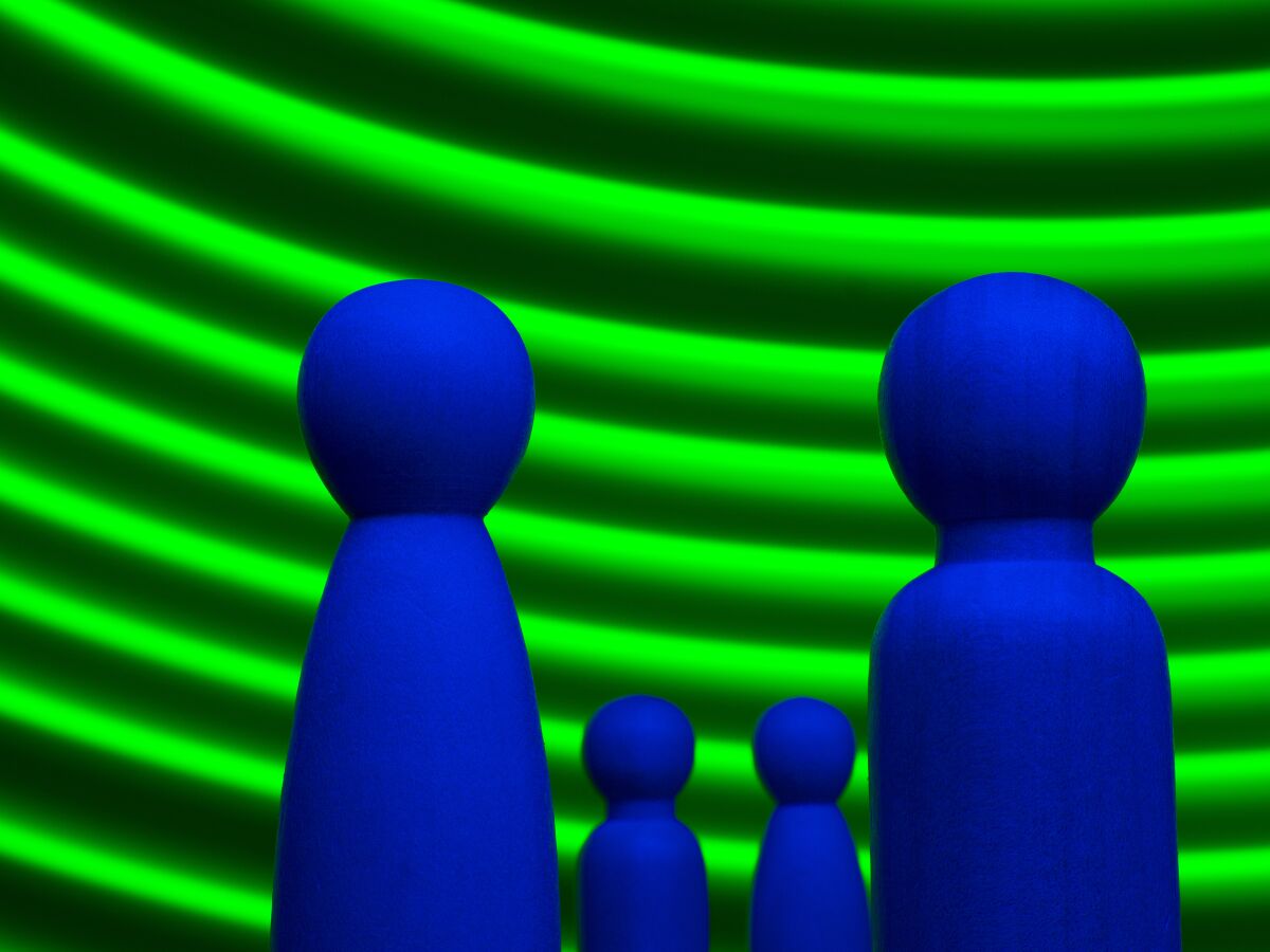 Couple with two small children represented by wooden figures with curved green lines in the background.