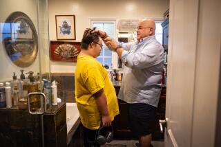 Los Angeles, CA - August 08: Fernando Gomez, cofounder of Integrated Community Collaborative, combs his son Oscar Antonio's hair on Thursday, Aug. 8, 2024 in Los Angeles, CA. (Jason Armond / Los Angeles Times)