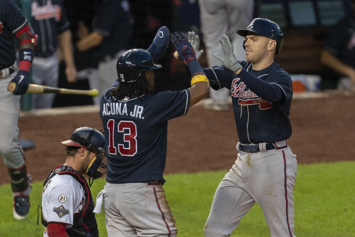 Atlanta Braves' Freddie Freeman, right, is congratulated at home plate by teammate Ronald Acuna Jr. (13) next to Washington Nationals catcher Yan Gomes, left, after hitting a two-run home run during the fourth inning of a baseball game in Washington, Thursday, Sept. 10, 2020. (AP Photo/Manuel Balce Ceneta)