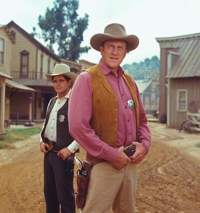 Actors Arness, as Marshal Matt Dillon in foreground, and Buck Taylor as Newly O'Brien from the television series "Gunsmoke" in 1970. See obituary