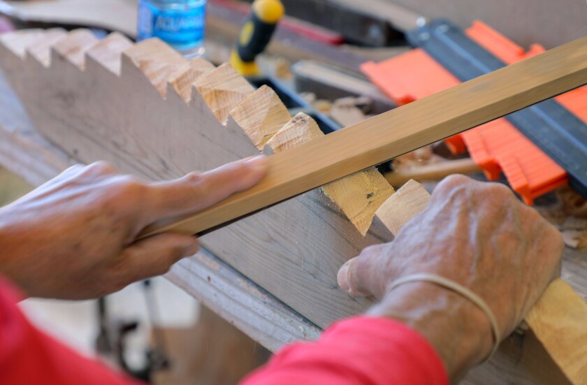 Tom Kottmeier sands a piece of cedar he's making into one of the frames of his replica Viking ship.