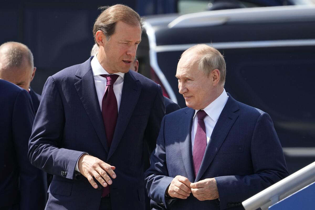 FILE - Russian President Vladimir Putin, right, and Russian Industry and Trade Minister Denis Manturov arrive to attend the opening of the MAKS-2021 International Aviation and Space Salon in Zhukovsky outside Zhukovsky, Russia, Tuesday, July 20, 2021. Russian President Vladimir Putin on Friday replaced Russian Roscosmos head Dmitry Rogozin with Yuri Borisov, a deputy prime minister who was in charge of weapons industries. Borisov's duties were handed over to Denis Manturov, the minister of industry and trade who was also given the rank of a deputy prime minister. (AP Photo/Alexander Zemlianichenko, Pool, File)