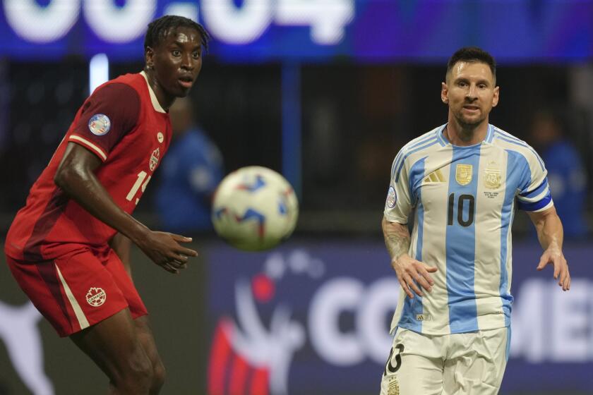 El delantero argentino Lionel Messi (derecha) y el zaguero canadiense Mo?se Bombito observan el balón durante el partido del Grupo A de la Copa América, el jueves 20 de junio de 2024, en Atlanta. (AP Foto/Jason Allen)
