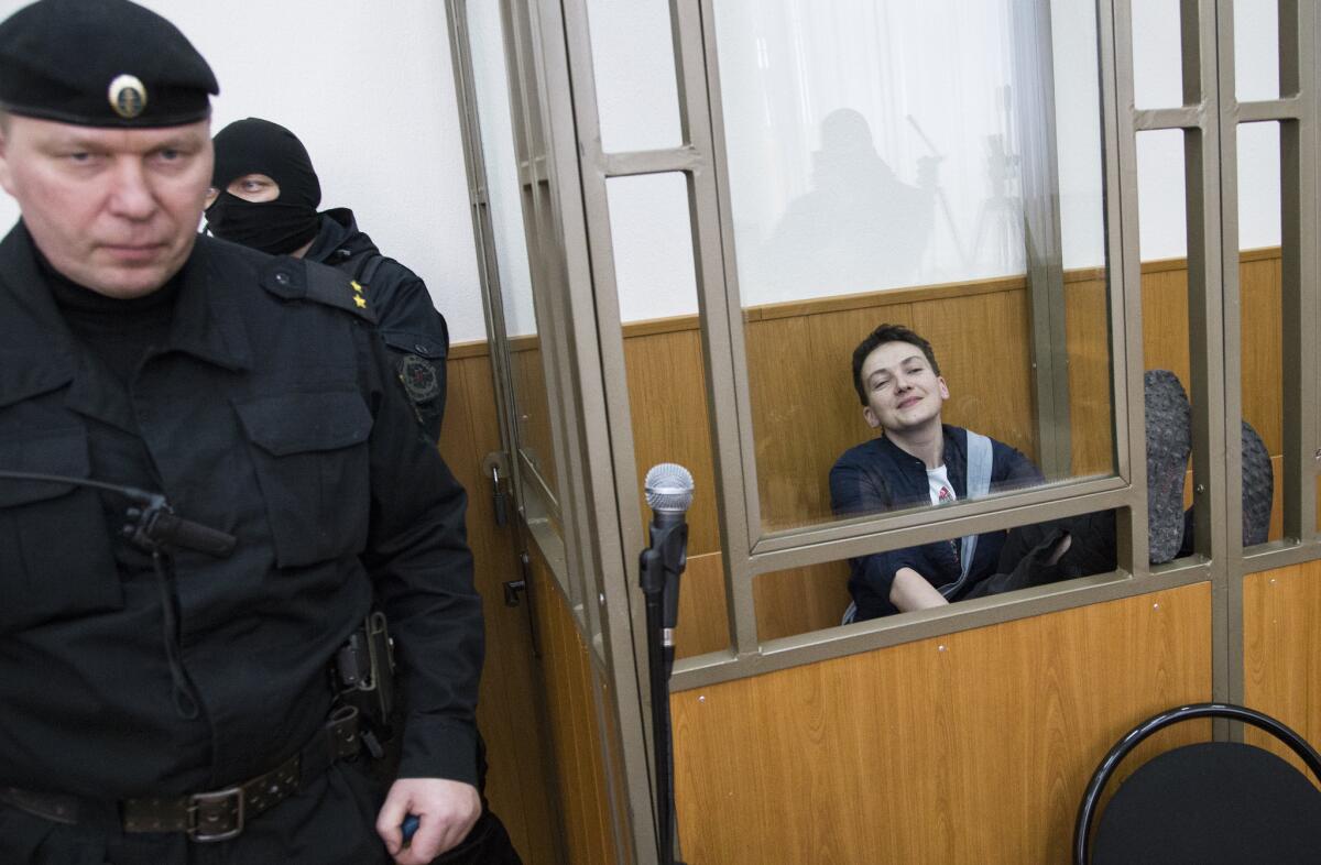 Ukrainian pilot Nadezhda Savchenko, right, smiles in a glass cage inside a court in Donetsk in March.