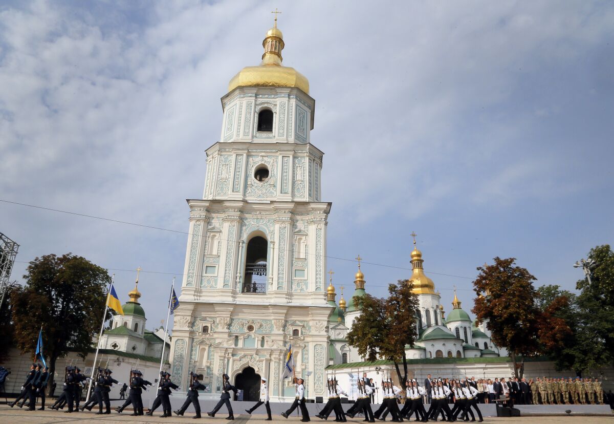 FILE - Ukrainian honor guard soldiers march past President Petro Poroshenko, background, in front of St. Sophia Cathedral in Kiev, Ukraine, Tuesday, Aug. 23, 2016, during State Flag Day celebrations. As the capital braces for a Russian attack in 2022, the spiritual heart of Ukraine could be at risk. (AP Photo/Efrem Lukatsky, File)