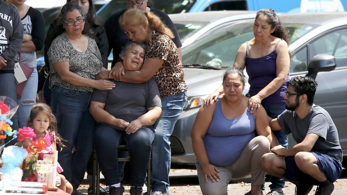 Relatives and friends grieve beside a makeshift memorial at the intersection of 9th Street and Locust Avenue in Long Beach, where a mother and daughter were shot and killed on Saturday night.