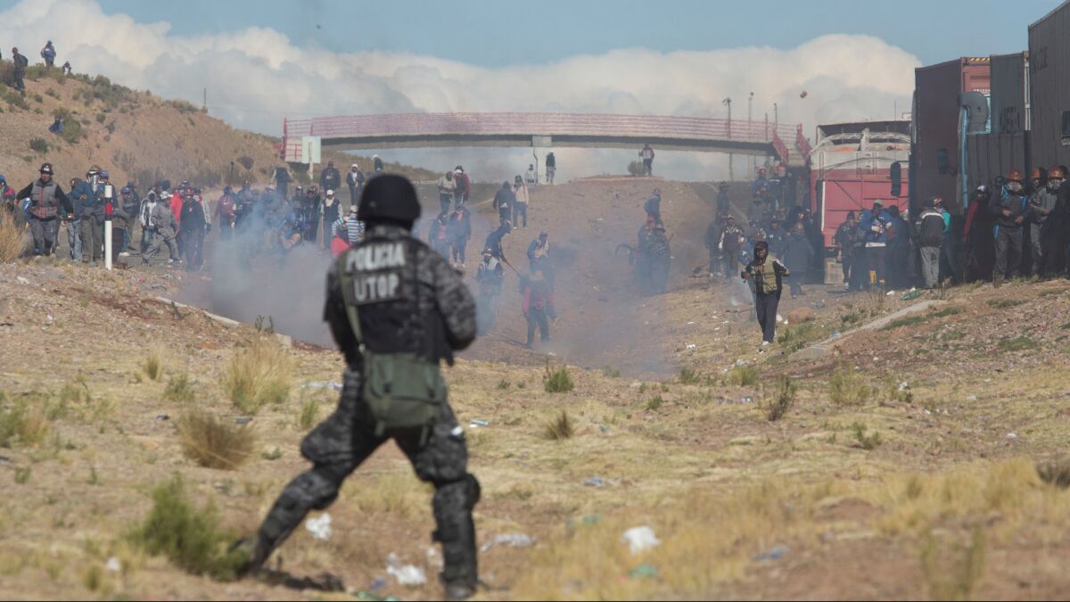 Miners clash with the police as they run from clouds of tear gas during protests in Panduro, Bolivia, on Thursday.