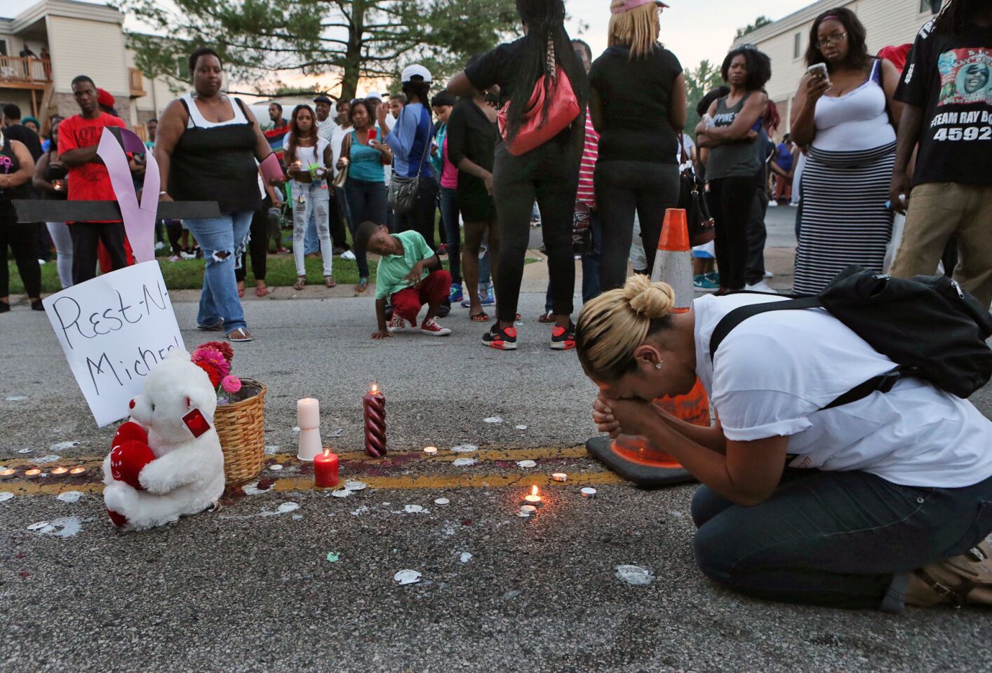 Meghan O'Donnell prays at the spot where Michael Brown was killed, Sunday evening in Ferguson, Mo.