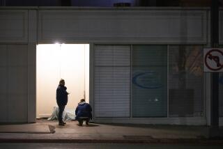 Volunteers try to talk to a homeless person before sunrise in a doorway in downtown on C Street across from San Diego City Hall, January 23, 2020 during the annual point-in-time homeless count.