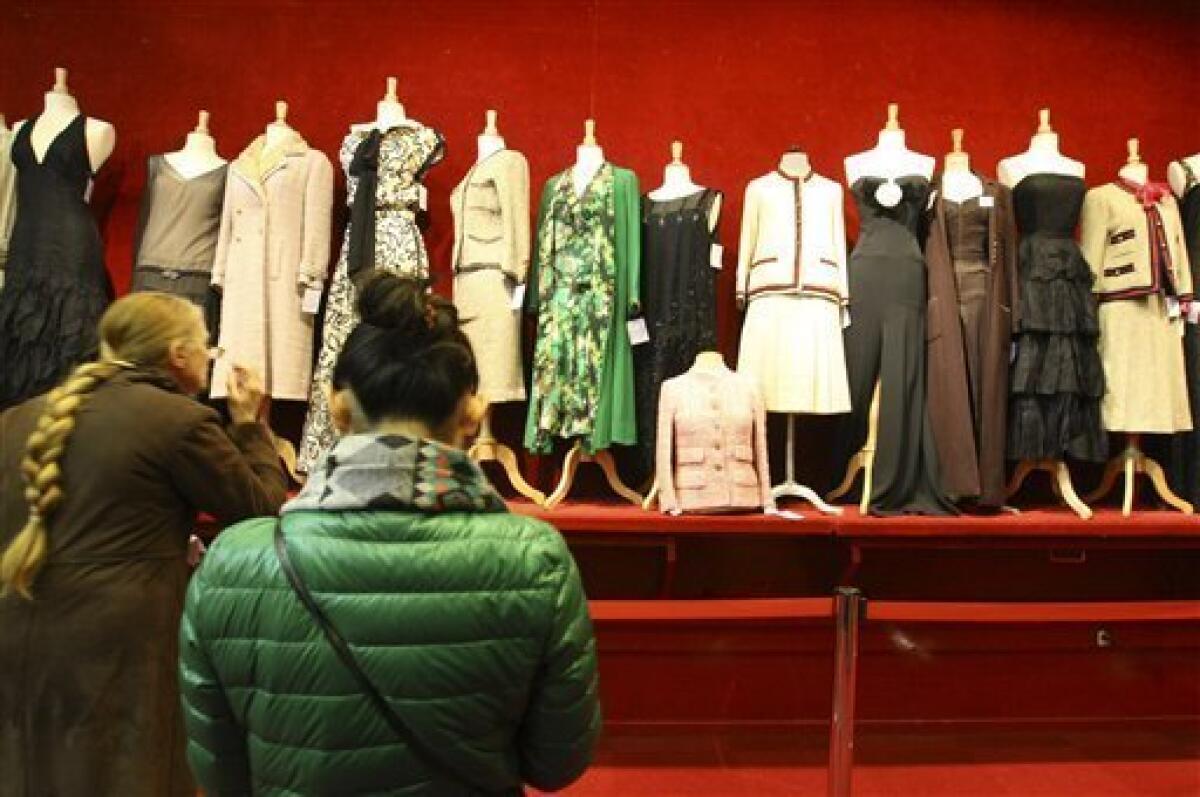 Visitors watch Chanel dresses exhibited at a Paris auction house, Thursday Feb. 25, 2010. Some 600 garments, accessories and shoes by the storied luxury giant Chanel hit Paris' auction blocks, with lots at the two-day-long sale including haute couture dresses designed by Mademoiselle Chanel herself. (AP Photo/Jacques Brinon)