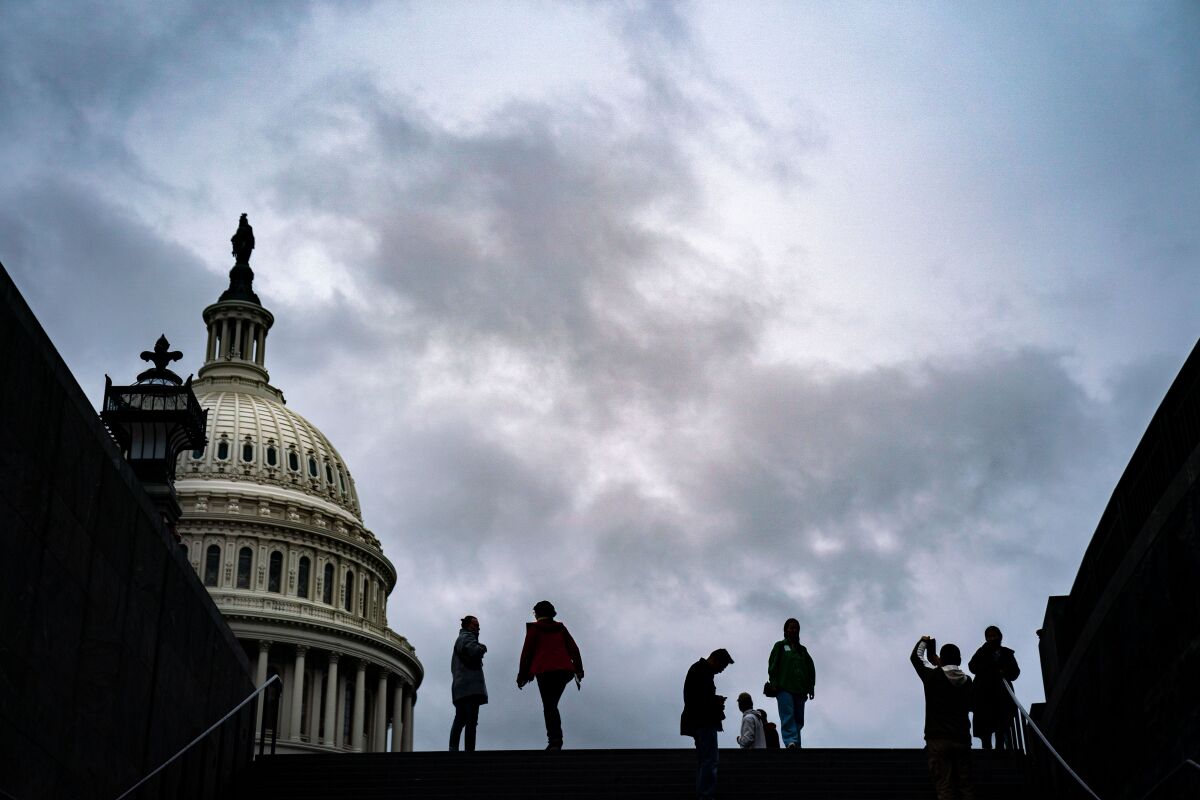 Visitors are cast in silhouette at the top of stairs near the Capitol 