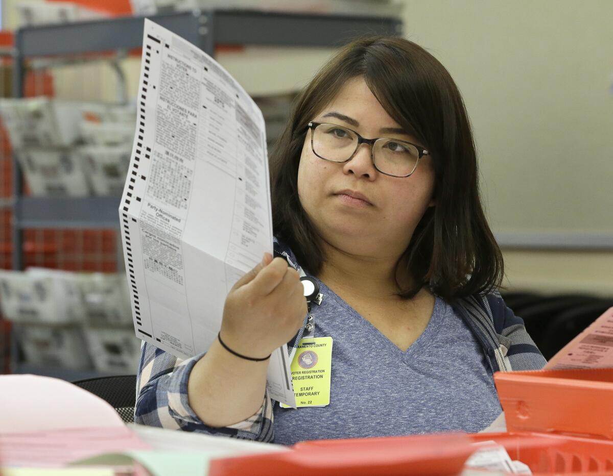 San Li inspects a mail-in ballot before it is counted at the Sacramento County Registrar of Voters office on June 10, 2016.