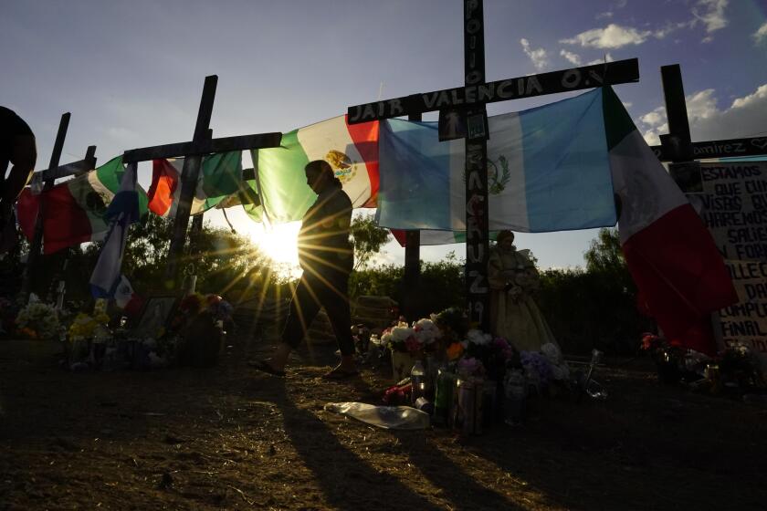 FILE - Mourners visit a make-shift memorial to honor the victims and survivors of a human smuggling tragedy in which dozens of migrants were found dead or dying in a tractor-trailer a week prior, July 6, 2022, in San Antonio. (AP Photo/Eric Gay, File)