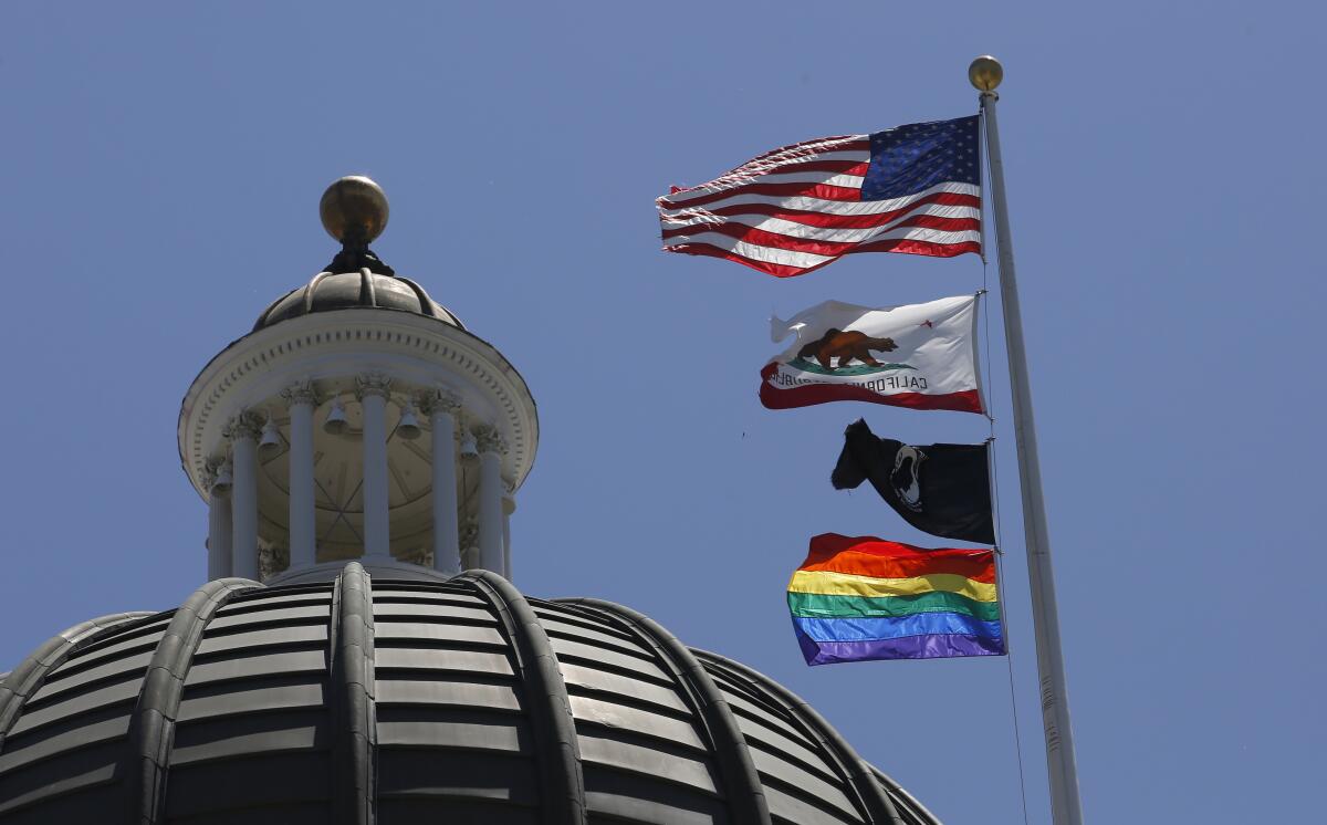 The American, California, POW-MIA and LGBTQ+ Pride flags fly at the state Capitol in Sacramento in 2019. 