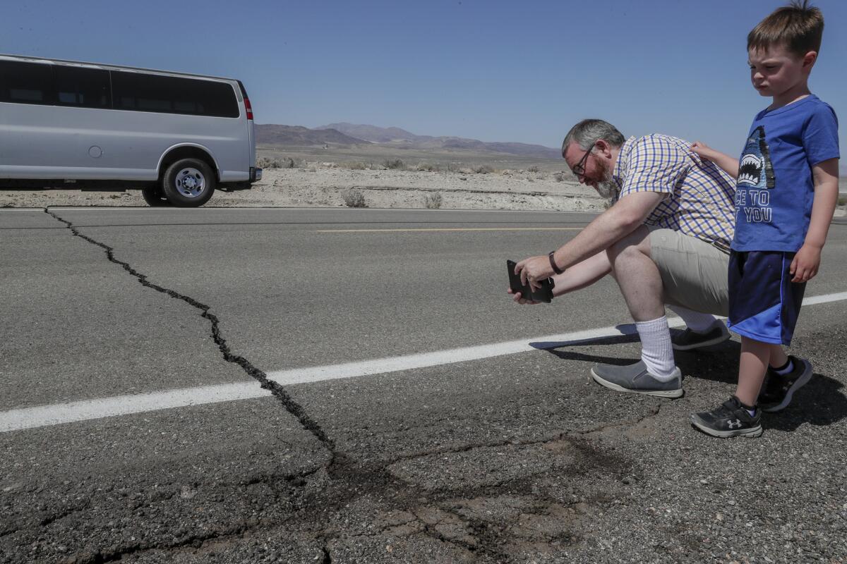 Andy Randolph and his son William stop for photos of a crack in California State Route 178 hours after a 6.4 magnitude earthquake struck the Searles Valley area.
