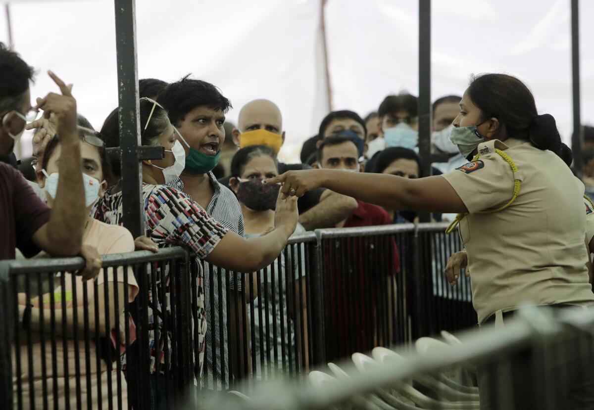 A man in a crowded line speaks with his mask pulled down