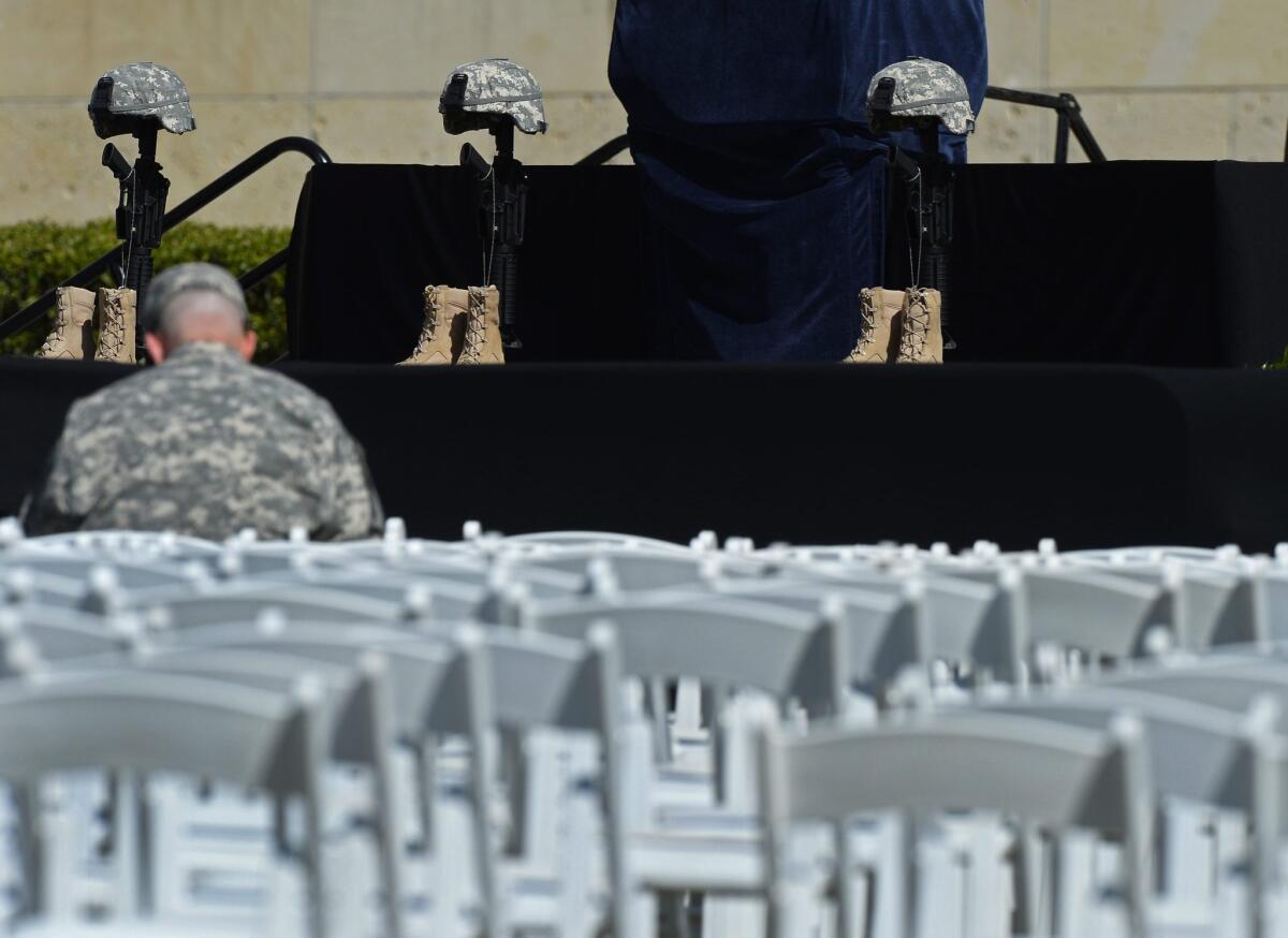 A soldier sits in front of the memorial representing the three troops killed in a shooting rampage last week at Ft. Hood in Texas. A memorial service will be held on the base Wednesday.