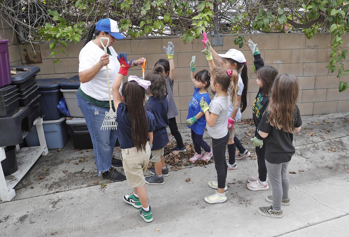 Daya Oyarzabal, left, helps kids from the Kinetic Academy "Green Team" choose tools as they pack and water garden boxes.