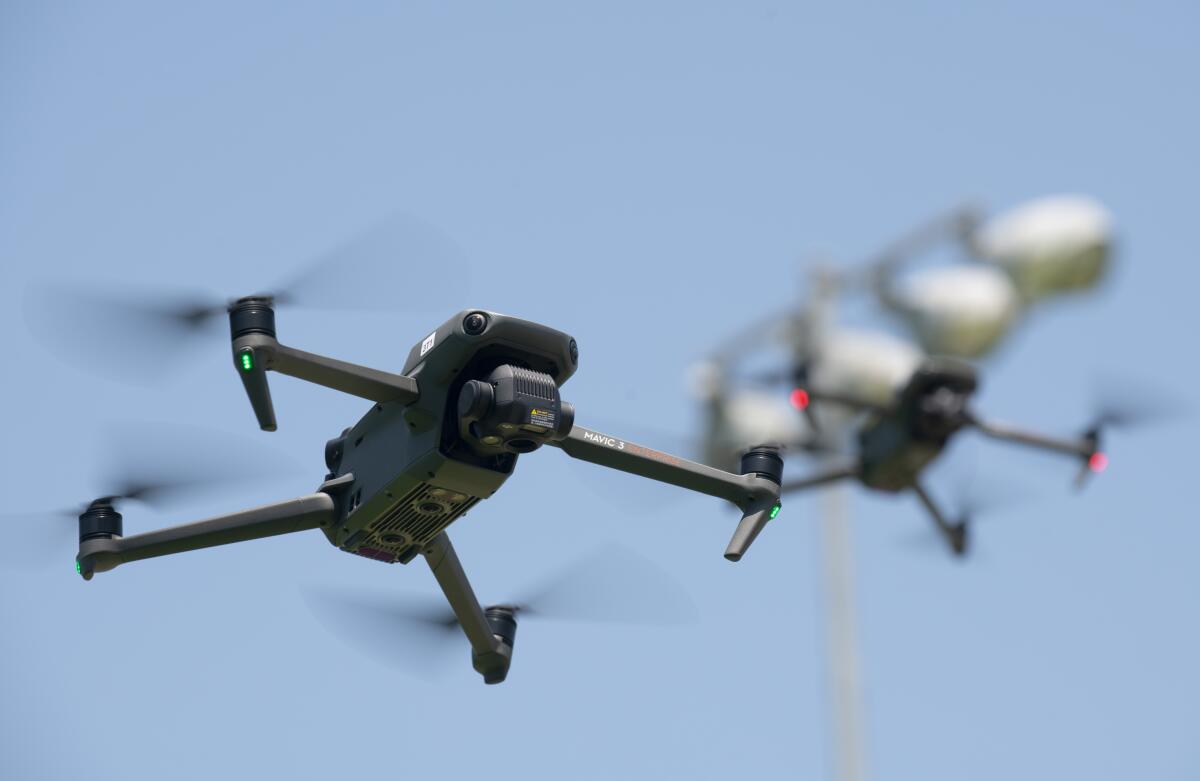 Fountain Valley Police Sgt. Brian Mosher and Officer Anthony Clements hold a pair of drones in formation.