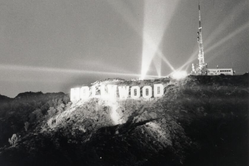 A historical photo of the Hollywood Sign lit up at night. 