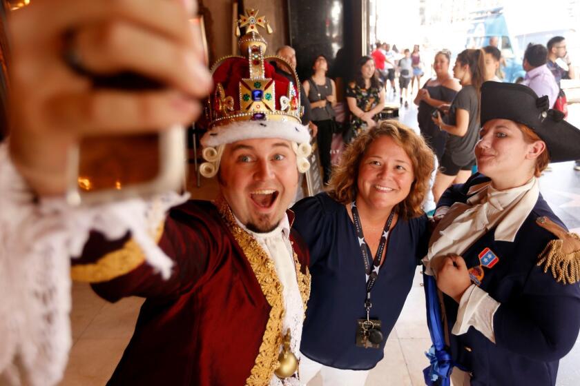 Chad Evett, as King George III, left, and Katie Aiani, as George Washington, right, take a selfie with Olivia Kimbley at the preview performance of, "Hamilton," at the Pantages Theatre in Hollywood.