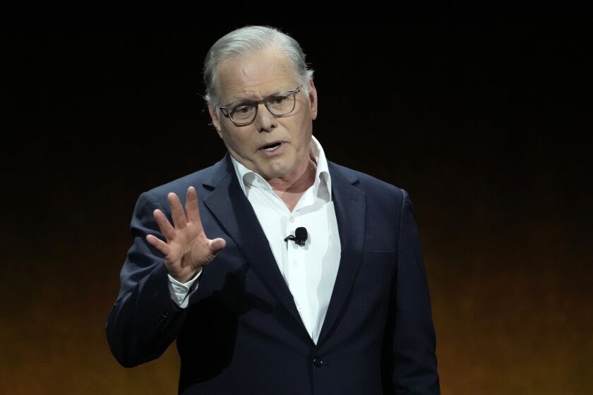 David Zaslav speaks and gestures while wearing a dark suit and glasses.